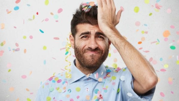 Man looking with regretful look into camera, keeping his hand on forehead.