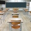 This is a Korean classroom without students. There are beige colored desks and a green chalkboard.