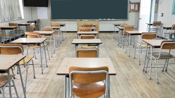 This is a Korean classroom without students. There are beige colored desks and a green chalkboard.