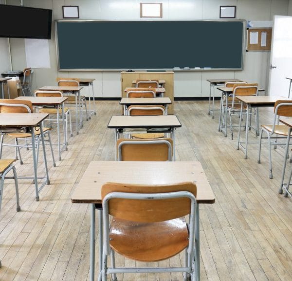 This is a Korean classroom without students. There are beige colored desks and a green chalkboard.