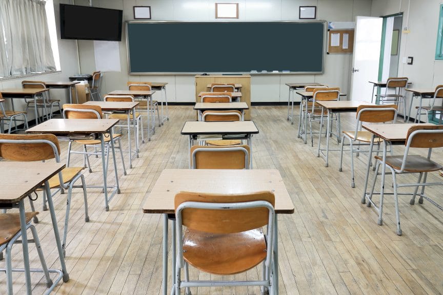 This is a Korean classroom without students. There are beige colored desks and a green chalkboard.