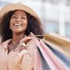 Black woman smiling while holding shopping bags.