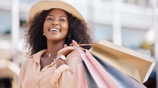 Black woman smiling while holding shopping bags.