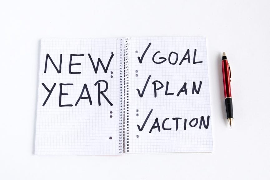 Notebook message that reads "New Year - Goal, Plan, Action" with each checked off.