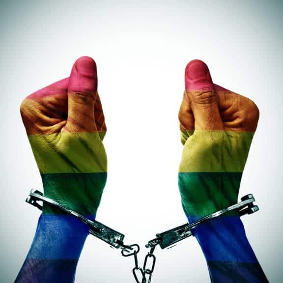 Two rainbow colored hands in handcuffs.