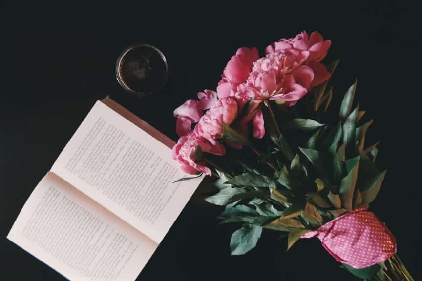 Bouquet of flowers next to opened book.