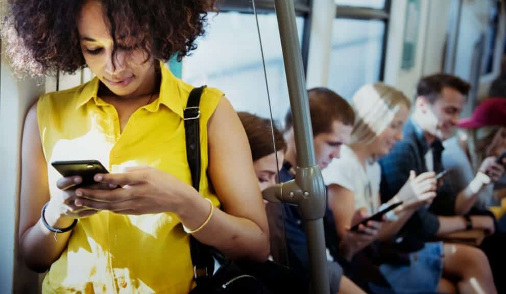 Woman is on her phone while standing on a crowded bus.