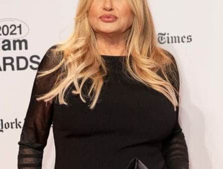 Image of Jennifer Coolidge standing on a red carpet with her lips perked.