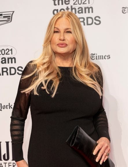 Image of Jennifer Coolidge standing on a red carpet with her lips perked.