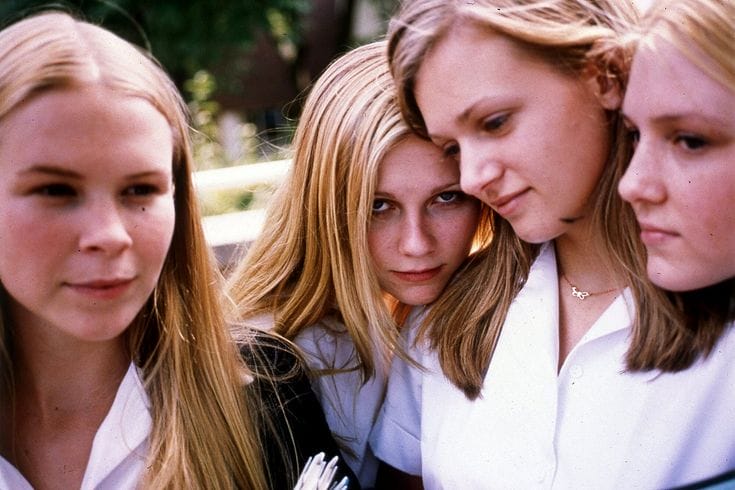 Four blonde girls in school uniforms huddled together.