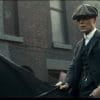 A white man in a flat cap and suit riding a horse