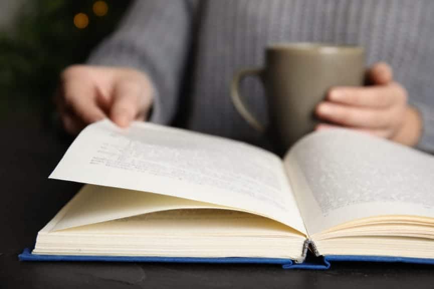 Woman reading a book while drinking tea