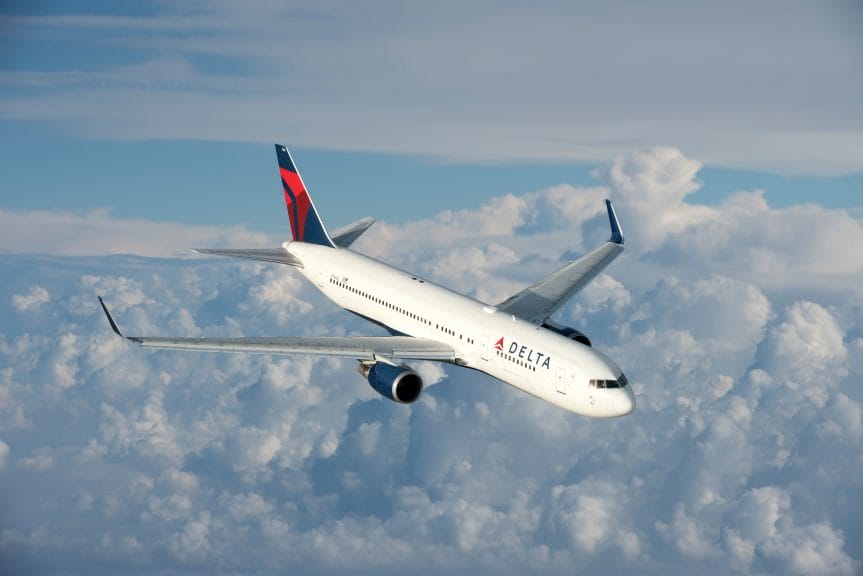 A Delta Airlines airplane flying in the sky against a background of clouds.