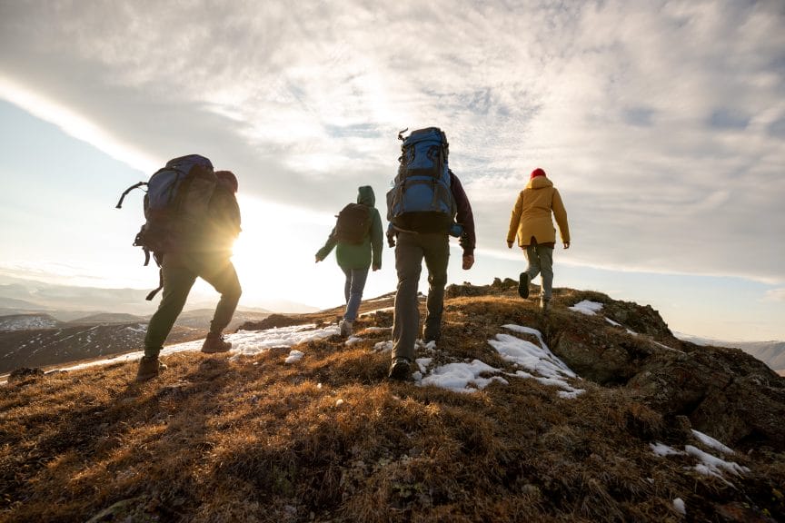 A group of four backpackers climbing up a mountain.