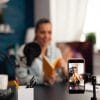 A woman recording a video of herself reviewing a book.