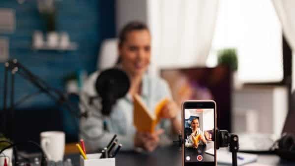 A woman recording a video of herself reviewing a book.