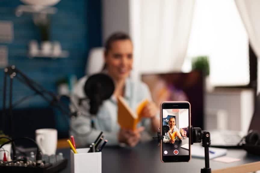 A woman recording a video of herself reviewing a book.