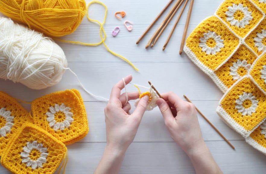 Image of hands crocheting with yellow and white wool,
