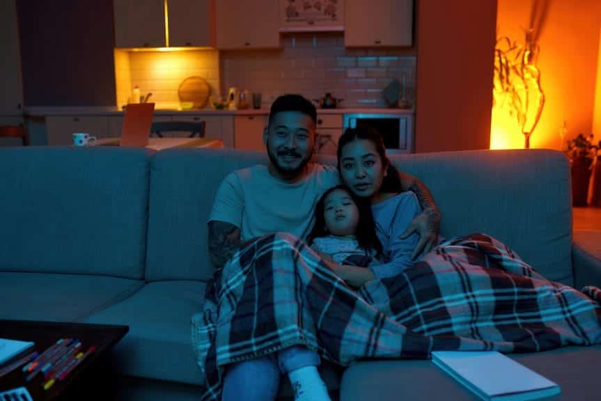 Family together on a couch watching television.