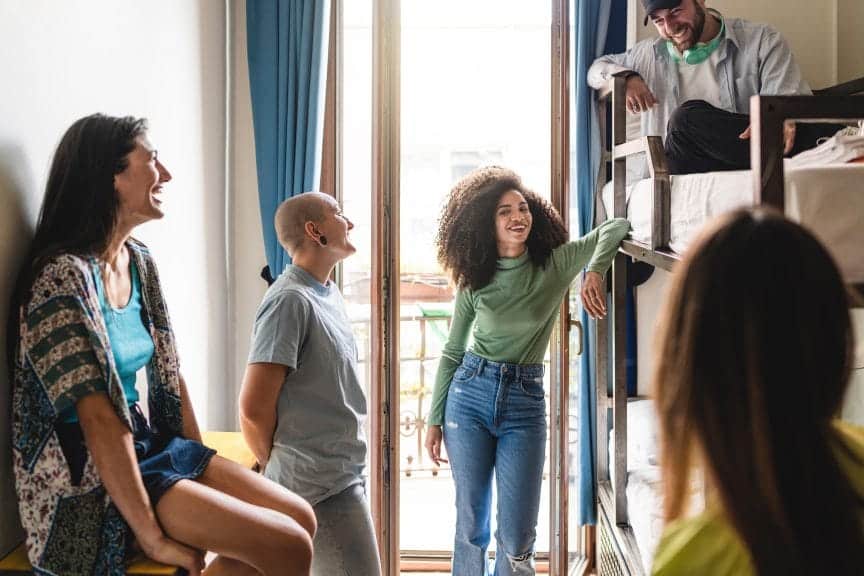 A group of people in a hostel, laughing and talking amongst each other.