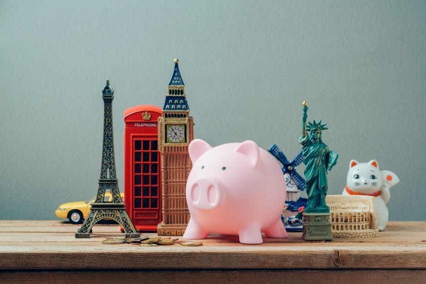 A piggybank placed among a display of miniatures of various landmarks and items from around the world.