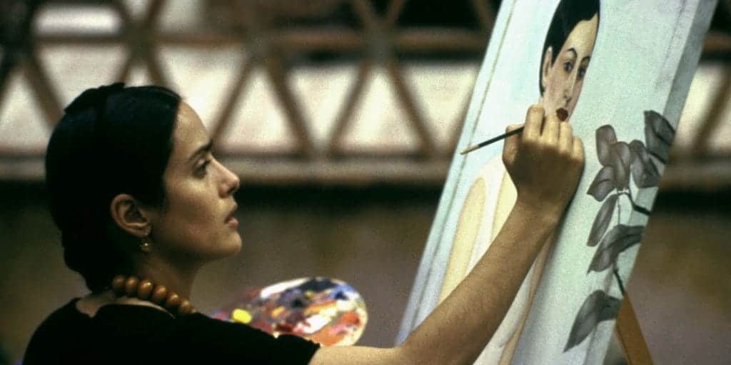 Frida Kahlo (Salma Hayek) works on a canvas.