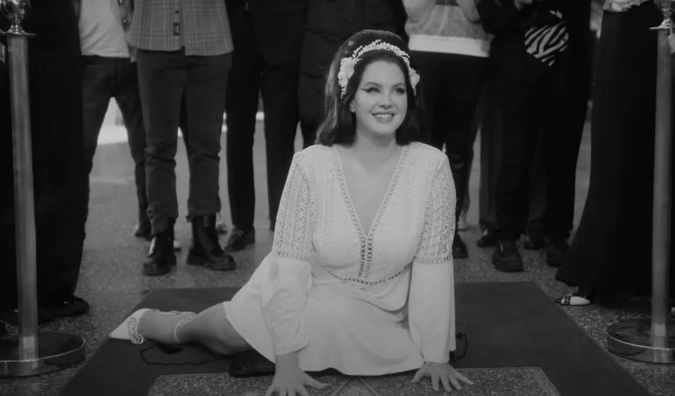 Lana Del Rey's music video for "Candy Necklace" takes place in Hollywood. Lana is pictured here with her Hollywood Walk of Fame star. Wearing a white dress and white headband.