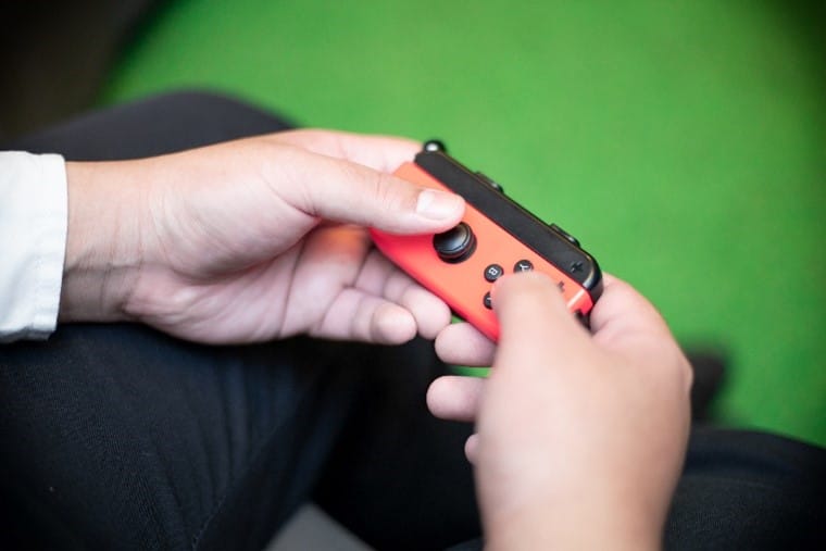 A red Nintendo Switch Joycon, detached from the console and being held by a player.