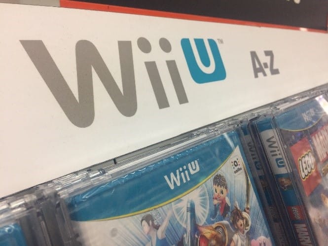 The Wii U logo on an aisle in a gaming store, above a selection of Nintendo games for the Wii U.