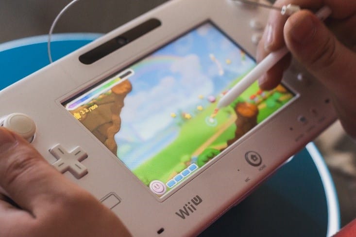 A person playing Mario Maker on a Wii U gamepad and holding a stylus.