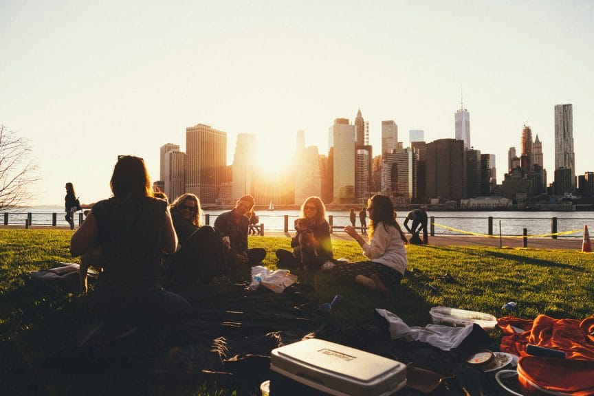 Five friends studying outside together at sunset next to a lake.