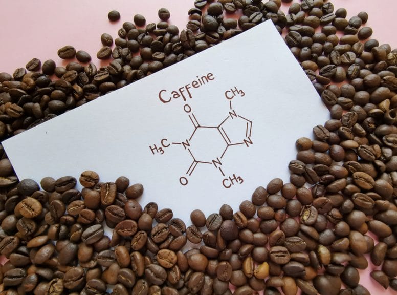 Piece of paper with the caffeine molecule drawn on it, surrounded by coffee beans.