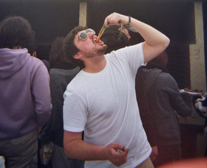 A man eating a calçot in a white t-shirt.