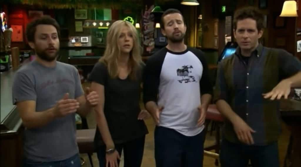 The gang from It's Always Sunny in Philadelphia is in the middle of singing together in their bar.