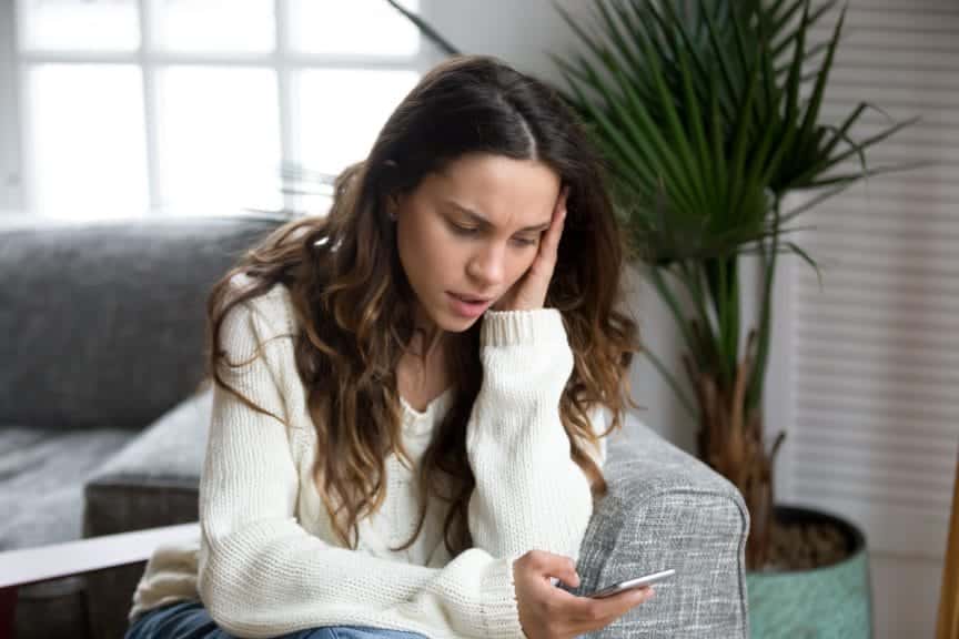 An upset woman looking at her phone.