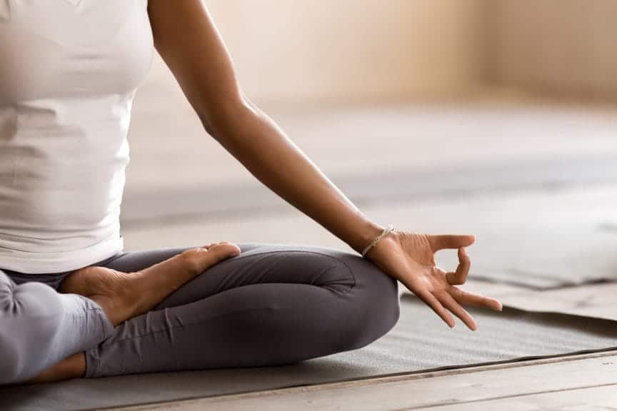 woman practicing yoga lesson, breathing, meditating, doing Ardha Padmasana exercise, Half Lotus pose with mudra gesture, working out, indoor close up.