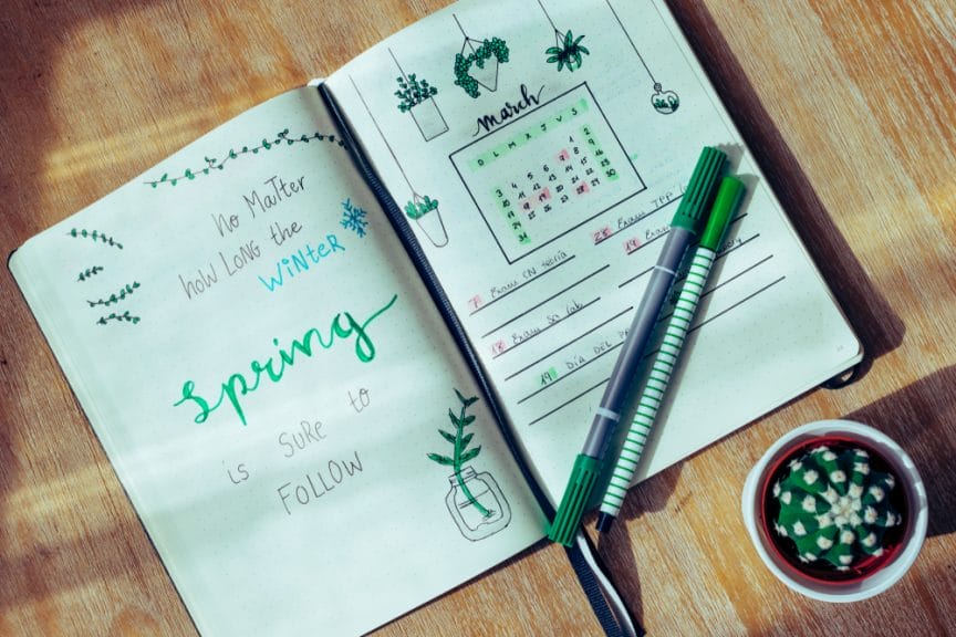 Spring Bucketlist Bullet Journal with Spring Quote "No Matter How Long the Winter, Spring is sure to follow" on wooden table.