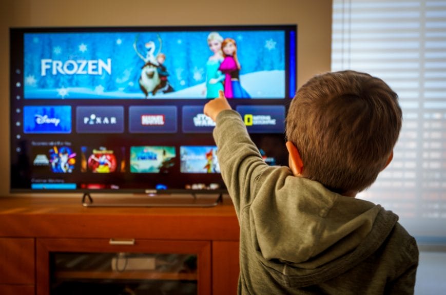 Kid pointing at the TV with children's movies on.