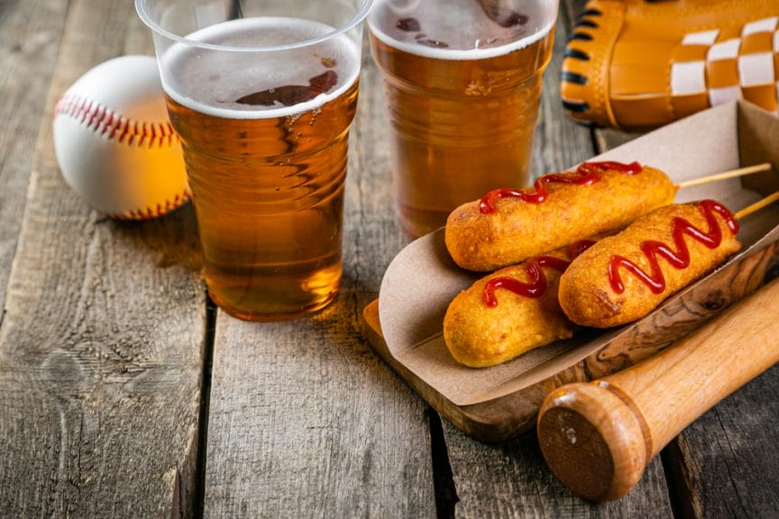 Beer, Corndogs, and baseball items on a wooden table