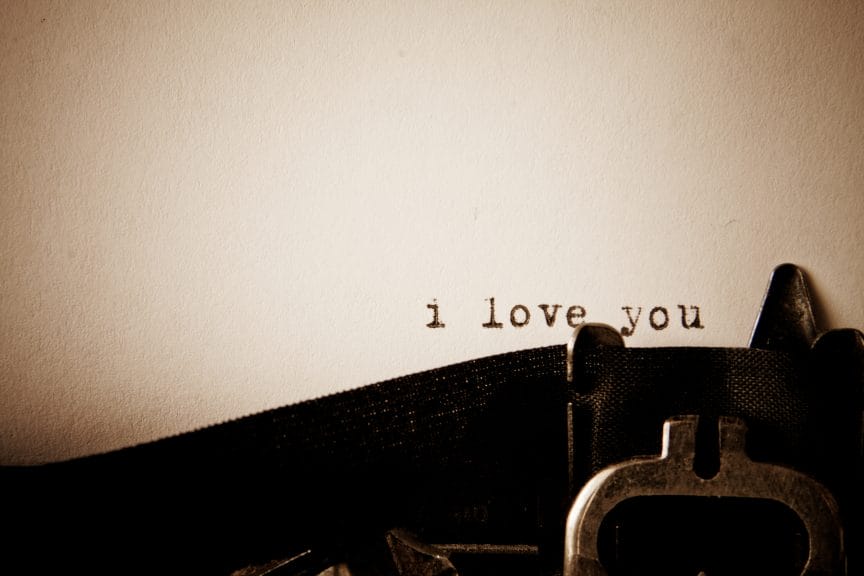 Dimly lit paper with a romantic typewriter message reading "i love you".