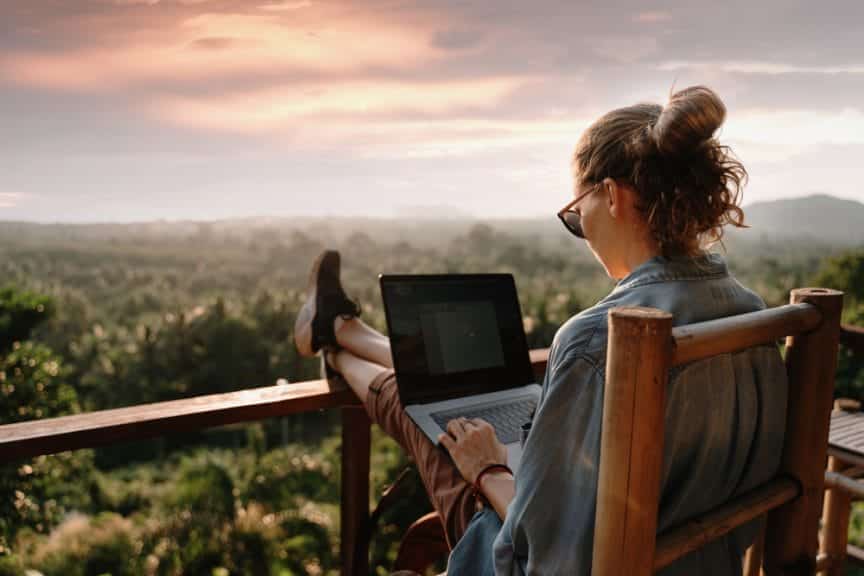 Young business woman working at the computer in cafe on the rock.