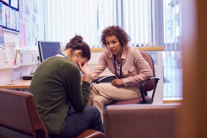 Two young woman, in a office, talking. Doctors are professionally trained to help with issues surrounding your mental health.