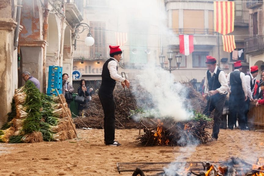 Men in traditional peasant dress cooking calçots in Valls, Spain.