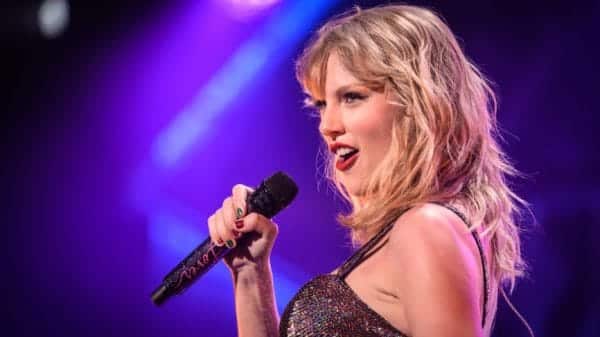 Taylor Swift singing a song on stage with a mike in hand.