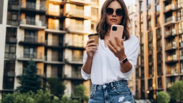 Portrait of a Successful Business woman Using iPhone pro with coffee cup.