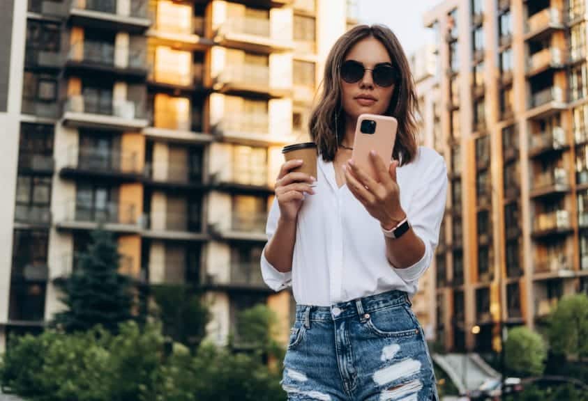 Portrait of a Successful Business woman Using iPhone pro with coffee cup.