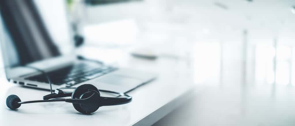 A desk, with a computer and headphones connected to the computer. Hotlines are there to help if you're having a hard time managing your mental health.