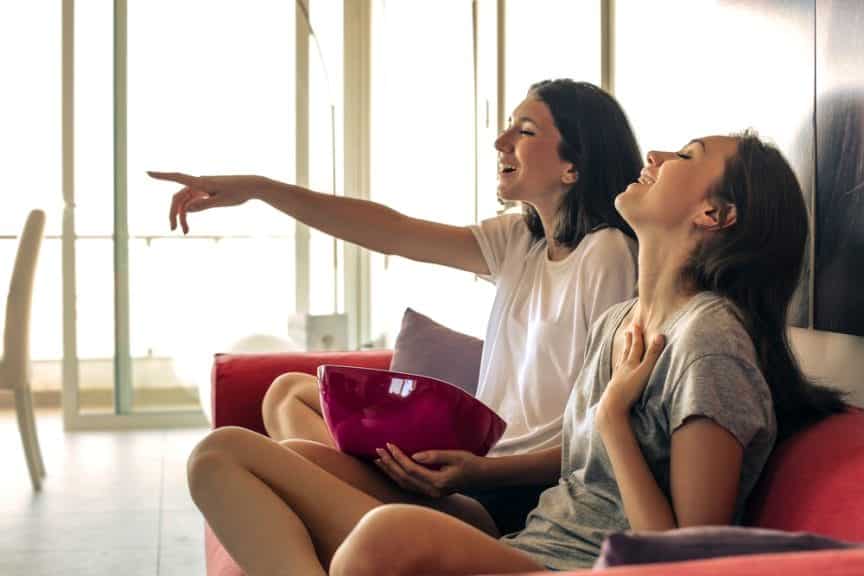 two girls laughing, watching movie