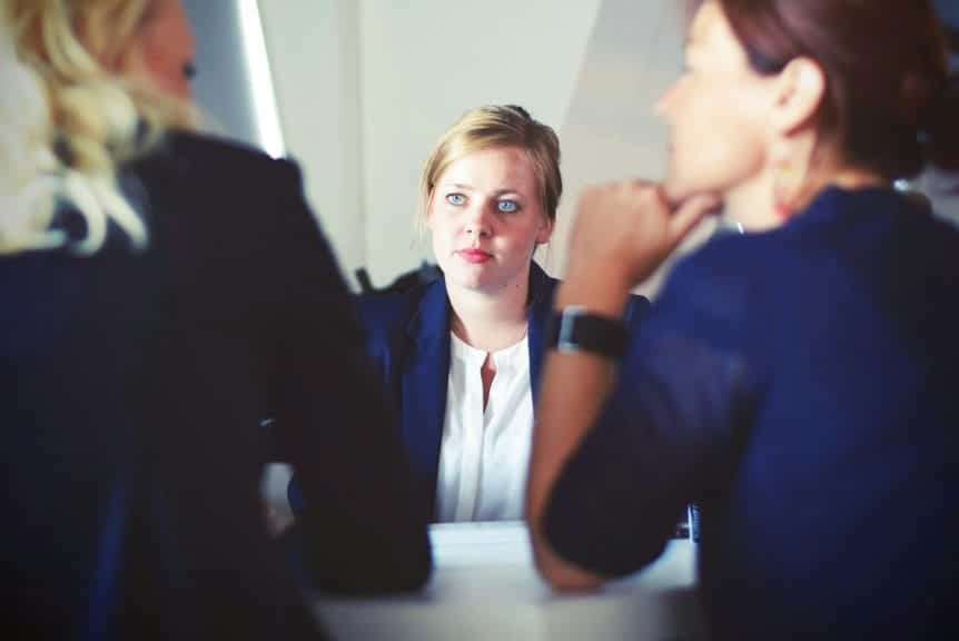 A woman sitting across from two people interviewing for a job