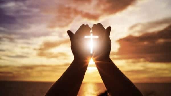 Prayer hands in front of Ocean.